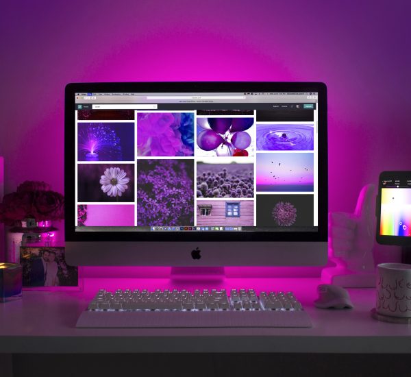 Showing a computer screen and keyboard on a desk agains a purple background.